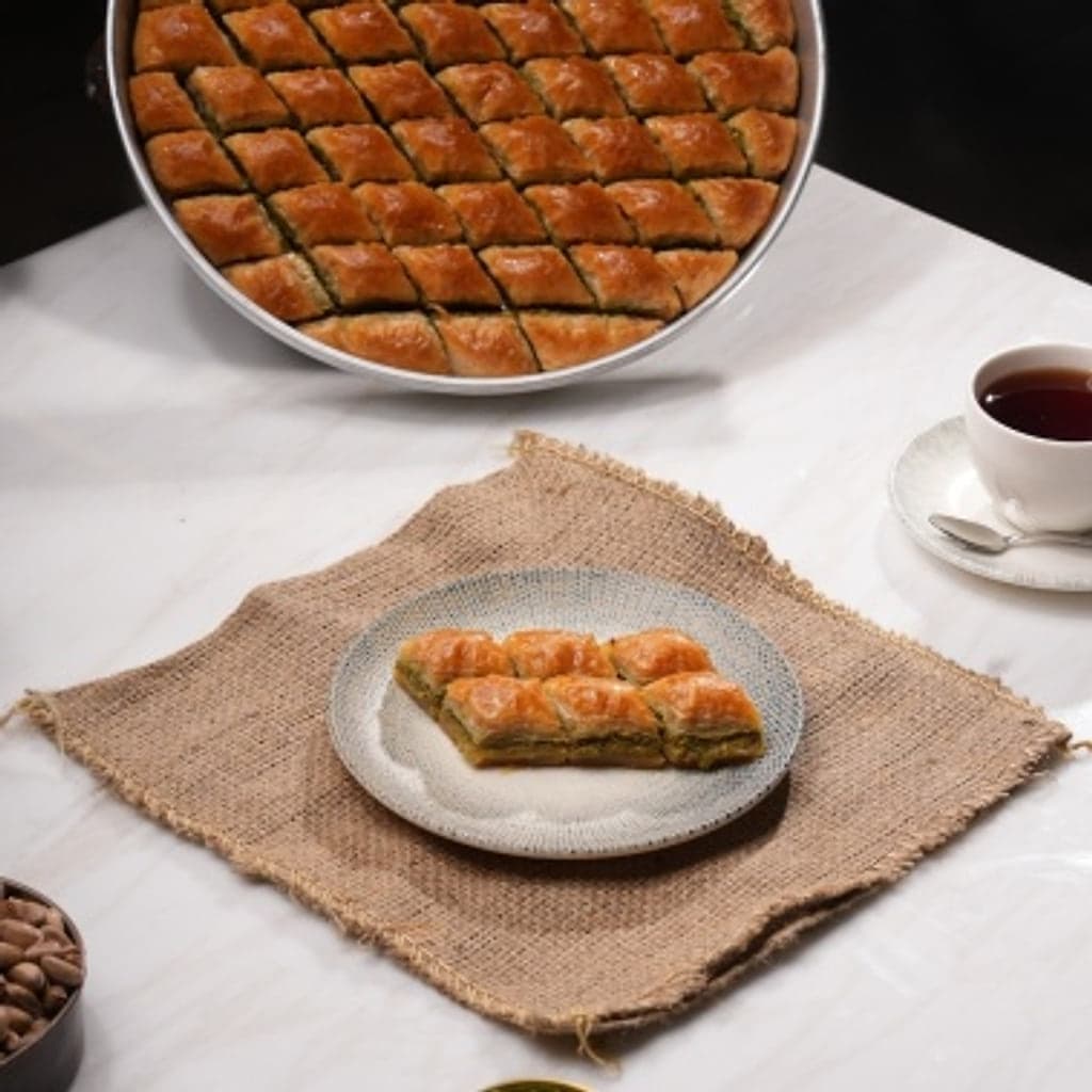 Fıstıklı klasik baklava, bakır tepside ve çay eşliğinde sofrada